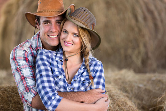 young farming couple hugging in barn