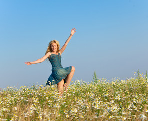 The happy young woman in the field of camomiles