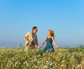 Fototapeta premium The happy young pair in the field of chamomiles