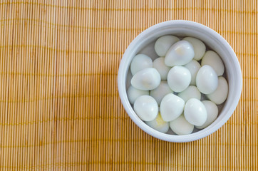 boiled quail eggs in a small bowl on a bamboo mat