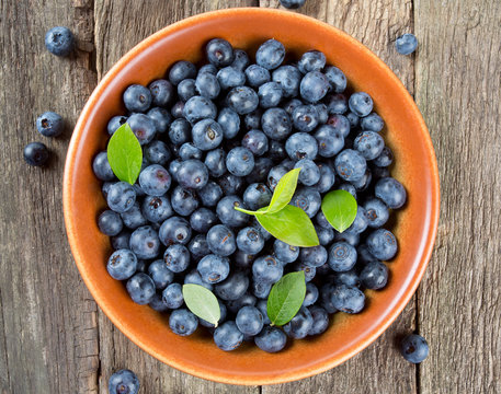 fresh blueberries in a bowl on wooden surface