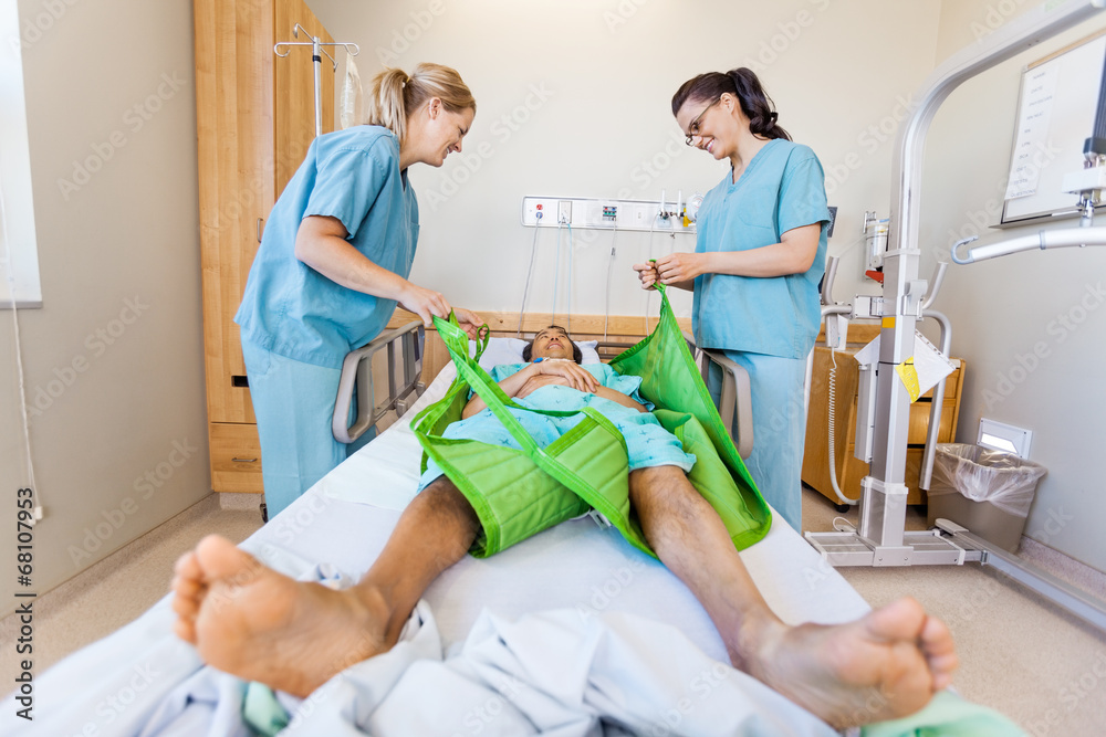 Wall mural Nurses Preparing Male Patient Before Transferring Him On Sling L