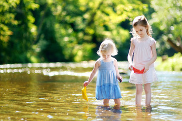 Two little sisters playing with paper boats