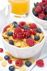 cornflakes with berries in a bowl, milk and orange juice