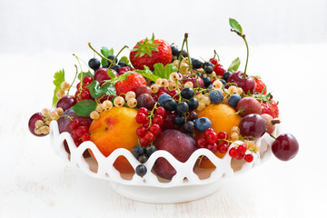 dish with seasonal fruit and berries on white table