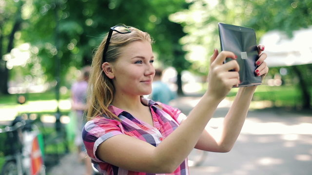 Young teenager taking photos with tablet computer in city park