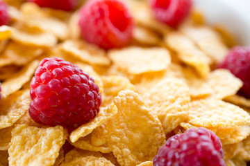 Cornflakes and red rasberries in a white bowl