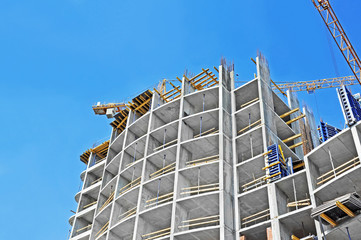Crane and building construction site against blue sky