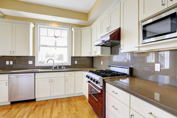 White kitchen with burgundy stove and grey counter tops