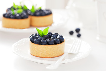 Tartlets with cream and blueberries, selective focus