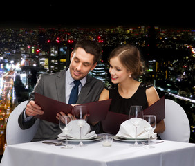 smiling couple with menus at restaurant