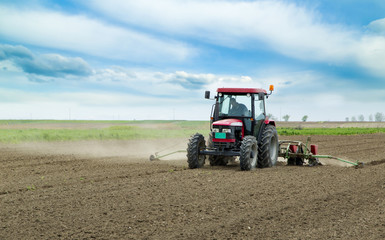 Fototapeta premium Young farmer sowing crops at field with pneumatic sowing machine
