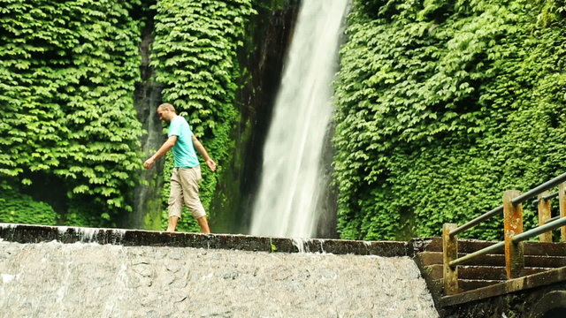 Man walking by beautiful waterfall, Bali, Indonesia