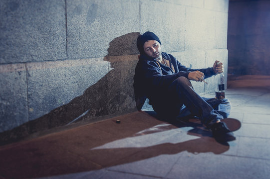 alcoholic drunk man sitting on street drinking alcohol
