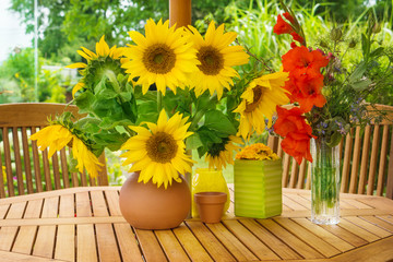 Sonnenblumen und Gladiolen auf Gartentisch