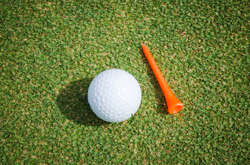 golf ball with orange tee on green grass