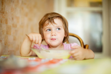 Fototapeta premium child eats from plate with spoon
