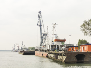 Shipyard with  stationed vessels and industrial cranes