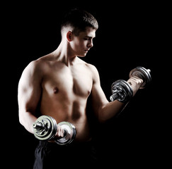 Young muscular sportsman with dumbbells on dark background