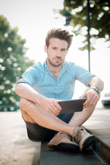 Obraz premium young handsome hipster modern man using tablet outdoor