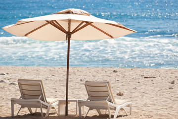 parasol et lits de soleil sur plage de sable blanc
