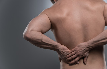 back of young shirtless man with back pain.