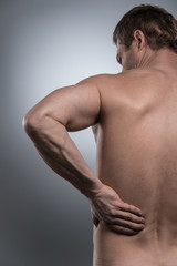 back view of young shirtless man with back pain.