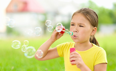 Little girl is blowing a soap bubbles