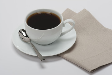 Black Coffee In White Cup On Folded Natural Linen Napkin. White