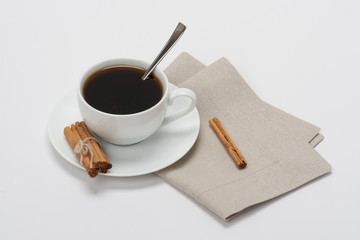 Black Coffee In White Cup And Cinnamon Sticks On Folded Natural