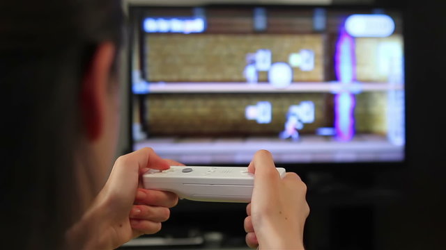 Teenager girl with games console playing video game.