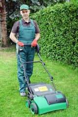 Gärtner mit Vertikutierer auf Rasen