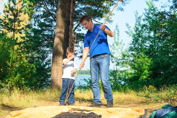 father and son put a tent in the camping