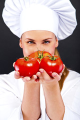 Portrait of young woman chef with tomatos