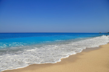 Fototapeta na wymiar Sandy seashore with blue sky and water