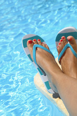 Female wet feet with flip flops by the pool
