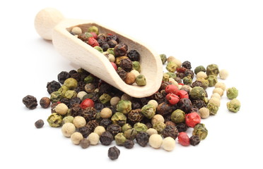 Colored pepper on a wooden spoon isolated on white background