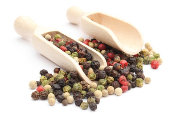 Colored pepper on a wooden spoon isolated on white background