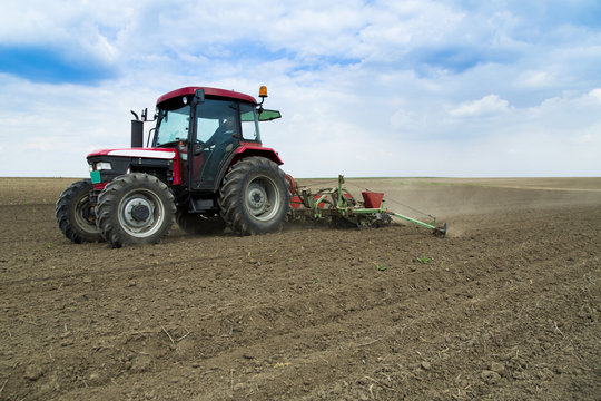 Tractor seeding crops at field.