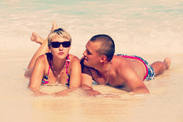 Young romantic couple laying on sandy beach