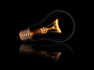 Lit light bulb on black background