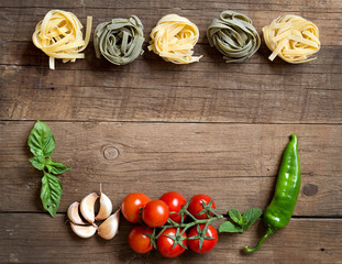 Pasta, vegetables and herbs on wood