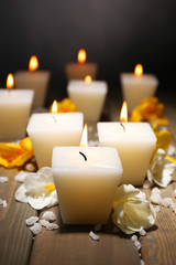 Beautiful candles with flowers on wooden background