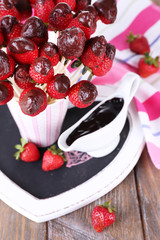 Strawberry in chocolate on skewers in cup on table close-up