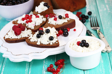 Bread with cottage cheese and berries on wooden tray close-up