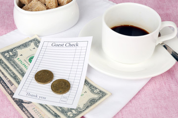 Check, cup of coffee and money on table close-up