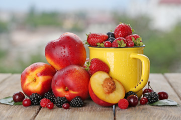 Peaches and berries on table on natural background