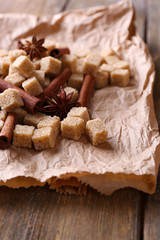 Brown sugar cubes and spices on paper background