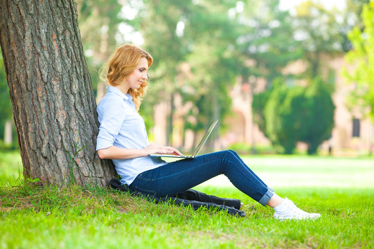 Beautiful Woman Sitting In Park With Laptop