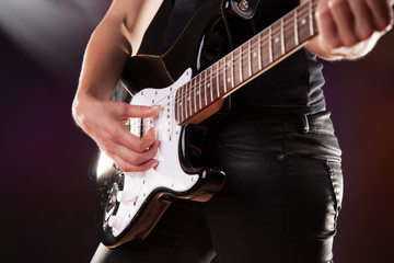 Woman playing on electric guitar in detail